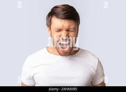 Ritratto di Emotional Man urlando furiosamente su sfondo bianco Foto Stock