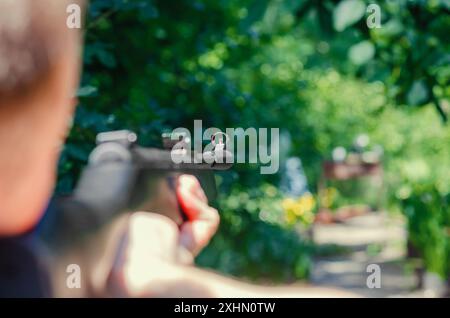 L'uomo sta tenendo la pistola e puntando. Primo piano del campo di tiro. Messa a fuoco selettiva. Caccia, sport, armi Foto Stock