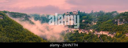 Un'ampia immagine panoramica 3:1 di una mattina presto con nuvole basse e nebbia durante l'alba a Rocamadour, una città e sito di pellegrinaggio in Francia. Rocamadour Foto Stock