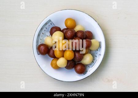 Deliziosi dolci del Bangladesh su un piatto bianco su sfondo di legno chiaro. Si chiama Baby Sweet perché di piccole dimensioni. Dolce molto succoso e gustoso. Foto Stock