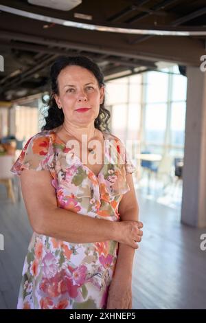 donna d'affari degli anni '60 in abito floreale in un moderno ufficio di coworking Foto Stock