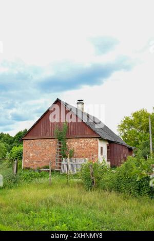 vecchia casa rustica in mattoni sullo sfondo della foresta Foto Stock