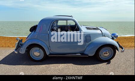 Fiat 500 classica parcheggiata sul lungomare, spiaggia e mare sullo sfondo. Foto Stock