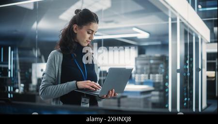 Responsabile del dipartimento di ingegneria del software tecnologico che utilizza un computer portatile. Donna multietnica che guarda a distanza e pensa mentre lavora in ufficio Foto Stock