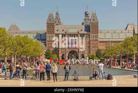 Amsterdam, Paesi Bassi - 15 maggio 2018: Gruppo di persone di fronte al Rijksmuseum Museo Nazionale olandese delle Arti e della storia Vista sullo stagno d'acqua. Foto Stock