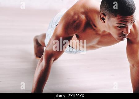 Persona concentrata che fa push-up, con una struttura muscolare e capelli corti. La sua espressione determinata mette in evidenza il suo impegno verso un rigoroso exer fisico Foto Stock