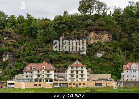 Una fila di case con una grande collina sullo sfondo. Le case sono tutte di dimensioni e stili diversi, ma hanno tutte uno schema di colori simile. La collina Foto Stock