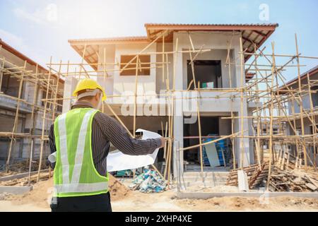 Ingegnere professionale architetto lavoratore con casco protettivo e blueprint di carta a casa costruzione edilizia di sfondo del sito Foto Stock