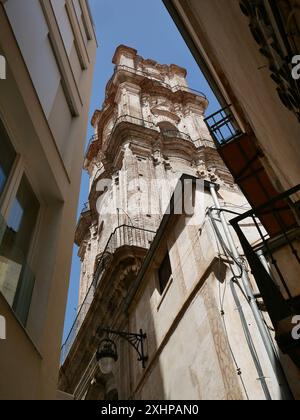 La chiesa di San Giovanni Battista si trova tra gli edifici vicini nel centro storico di Malaga, Andalusia, Spagna Foto Stock