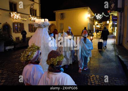 Francia, Alto Reno, Eguisheim, il Christkindel con la sua corona di candele e gli angeli accompagnano i molti bambini che tengono le loro lanterne per il Pro Foto Stock