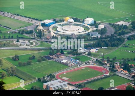 Un grande campo verde con uno stadio sullo sfondo. Lo stadio è circondato da una recinzione e ha una grande cupola bianca in cima. Il campo è anche surrou Foto Stock