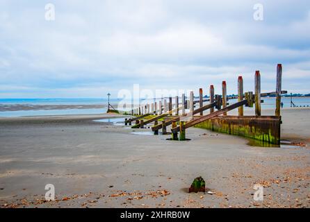 Uno sguardo lungo West Wittering UK Beach groynes in legno che conduce al mare Foto Stock