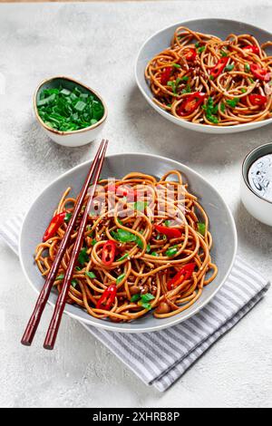 Tagliatelle di Udon, con funghi shimeji, verdure, in salsa, con semi di sesamo, cipolle verdi, cibo vegetariano asiatico, orizzontale, senza persone Foto Stock