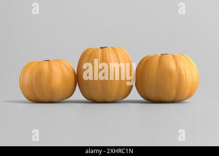 Tre zucche arancioni posizionate fianco a fianco su sfondo grigio Foto Stock