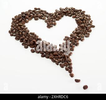 Chicchi di caffè, disposti a forma di cuore, su sfondo bianco Foto Stock