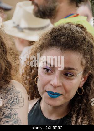 Primo piano di una donna con rossetto blu e capelli ricci tra la folla ad un evento Pride in una giornata di sole, editoriale gay Pride cremona italia 6 luglio 2024 Foto Stock