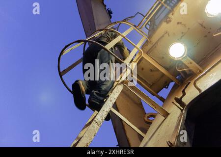 Borneo, Indonesia: Un lavoratore scende da una torre con la sua scala su una portarinfuse di carbone si ancorano al largo per il carbone nel Borneo in mare aperto Foto Stock