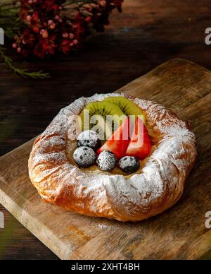 Pasticceria danese appena sfornata con marmellata e frutta. Sfondo di legno scuro. Foto Stock