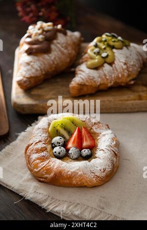 Pasticceria danese appena sfornata con marmellata e frutta. Sfondo di legno scuro. Foto Stock