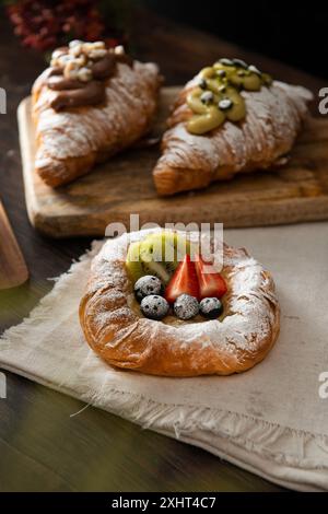 Pasticceria danese appena sfornata con marmellata e frutta. Sfondo di legno scuro. Foto Stock