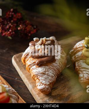 Croissant al cioccolato appena sfornati su sfondo di legno. Foto Stock