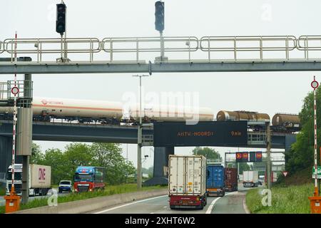 Gent, Belgio - 22 maggio 2023: Enormi pale di turbine eoliche trasportate su un carro di carico pesante lungo un'autostrada, passando sotto una limitazione di altezza Foto Stock