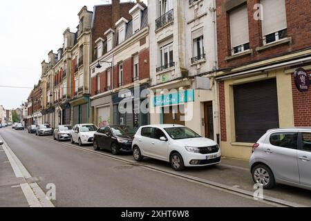 Cambrai, Francia - 21 maggio 2023: Le auto sono parcheggiate di fronte a una fila di negozi a Cambrai, Francia. I negozi hanno le loro persiane, il che suggerisce Foto Stock