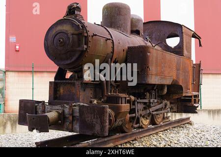 Una locomotiva a vapore arrugginita e inattiva è inattiva su una pista, la sua gloria sbiadita lascia intendere un'era ormai passata dell'industria. Foto Stock