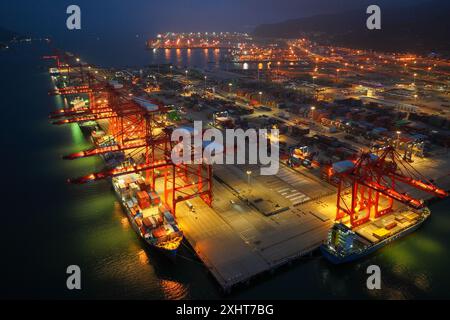 LIANYUNGANG, CINA - 15 LUGLIO 2024 - le navi cargo scaricano i container presso il terminal container del porto di Lianyungang, nella provincia di Jiangsu nella Cina orientale, luglio Foto Stock