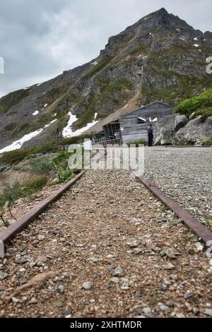 Palmer, Alaska - 14 luglio 2023: Binari ferroviari che conducono a strutture in legno di fronte a una montagna presso l'Independence Mine State Historical Park in Foto Stock