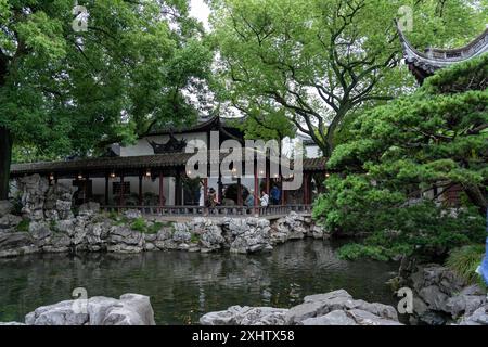 Shanghai, Cina - 06 giugno 2024: Un tranquillo laghetto circondato da vegetazione lussureggiante e dall'architettura tradizionale Cinese nel Giardino Yu di Shanghai. Foto Stock