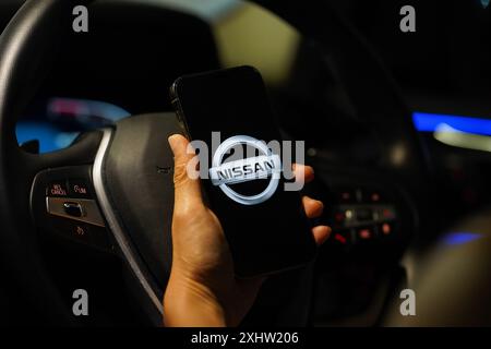 Hong Kong, Cina. 4 luglio 2024. In questa immagine, il logo di Nissan è visibile sullo schermo di uno smartphone con un volante sullo sfondo. Credito: SOPA Images Limited/Alamy Live News Foto Stock