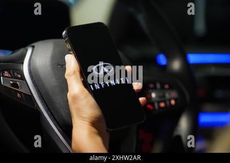 Hong Kong, Cina. 4 luglio 2024. In questa immagine, il logo di Infiniti è visibile sullo schermo di uno smartphone con un volante sullo sfondo. (Foto di Serene Lee/SOPA Images/Sipa USA) *** esclusivamente per notizie editoriali *** credito: SIPA USA/Alamy Live News Foto Stock