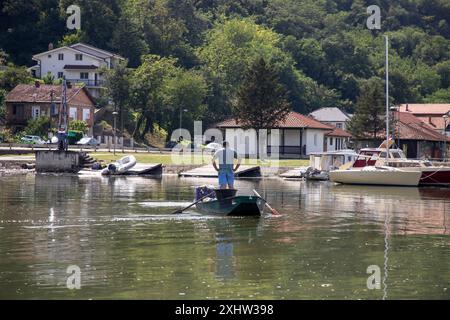 Il pescatore salpa sul fiume a bordo di una barca da pesca in stagno Foto Stock