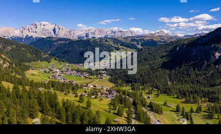 Incredibile vista su un drone dell'idilliaco paesaggio delle Dolomiti con prati verdi freschi, accoglienti case di paese e maestose cime di montagna. Foto Stock