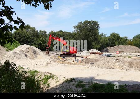 Un escavatore della JDB groep, una società olandese di ingegneria civile. Cantiere con tubi, tubi, pali di sabbia. Estate. Paesi Bassi, Bergen, luglio. Foto Stock