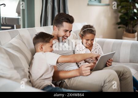 Papà, bambini e felici con un tablet a casa sul divano per giochi educativi, cartoni animati e intrattenimento. Persone, famiglia e sorrisi sul divano in soggiorno Foto Stock