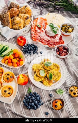 Picnic, antipasti e vassoio di formaggi e carne con muffin dolci e salati e frutta Foto Stock