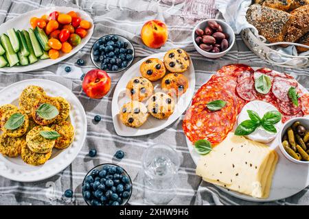 Picnic, antipasti e vassoio di formaggi e carne con muffin dolci e salati e frutta Foto Stock