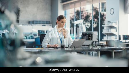 Ritratto della scienziata professionista che lavora in un laboratorio industriale utilizzando un computer portatile. Project Manager di successo che elabora piani strategici per l'azienda di produzione industriale, utilizzando la tecnologia Foto Stock