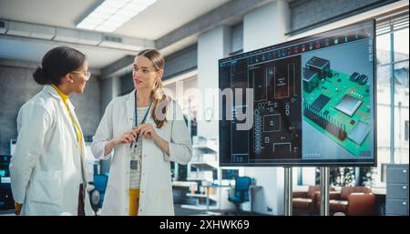 Giovane specialista donna entusiasta che fa una presentazione, che spiega un progetto 3D al suo collega in un laboratorio. Ingegnere professionista sicuro di sé che consegna le sue idee di produzione al suo Team Lead Foto Stock