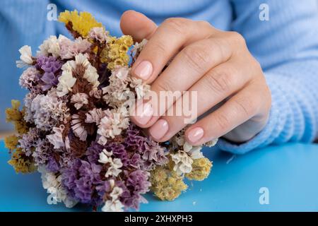 Unghie pastello morbide e curate su sfondo blu. Donna che mostra la sua nuova manicure nei colori della tavolozza pastello. Decorazioni semplici, fresche vibrazioni primaverili dai colori naturali Foto Stock