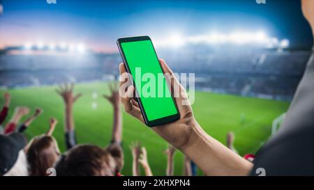 Sport Stadium Championship: Smartphone Chroma Key con schermo verde. Partita sportiva con i tifosi su Tribune tifo per la squadra preferita per vincere. Modello Copyspace per primi piani POV isolato. Foto Stock