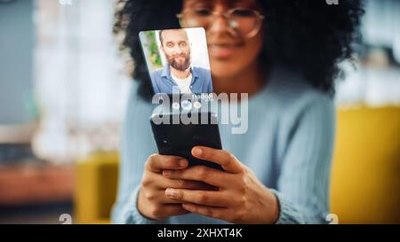 Concetto di incontri in realtà aumentata: Awesome Black Girl utilizza lo smartphone per la navigazione nell'app di incontri sui social media. Adorabile giovane donna brasiliana alla ricerca del vero amore con l'aiuto di software basato sull'intelligenza artificiale Foto Stock