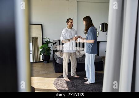 Una giovane coppia gay si gode un caffè mattutino nella loro camera da letto. Foto Stock