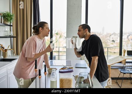 Una giovane coppia gay si gode un caffè mattutino insieme nella loro cucina moderna. Foto Stock