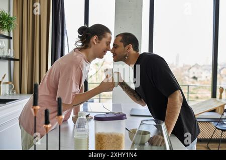 Una giovane coppia gay condivide un momento tenero mentre si gusta un caffè nella loro casa moderna. Foto Stock