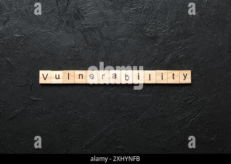 parola di vulnerabilità scritta su blocco di legno. testo della vulnerabilità nella tabella, concetto. Foto Stock