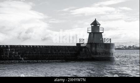 Torre del faro in piedi su una frangiflutti di cemento, ingresso al porto principale di Reykjavik, Islanda. Foto monocromatica sul mare Foto Stock