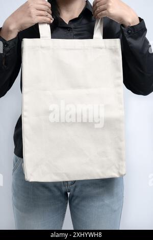 una donna che tiene in mano una borsa tote bianca vuota, utile per il design mockup Foto Stock